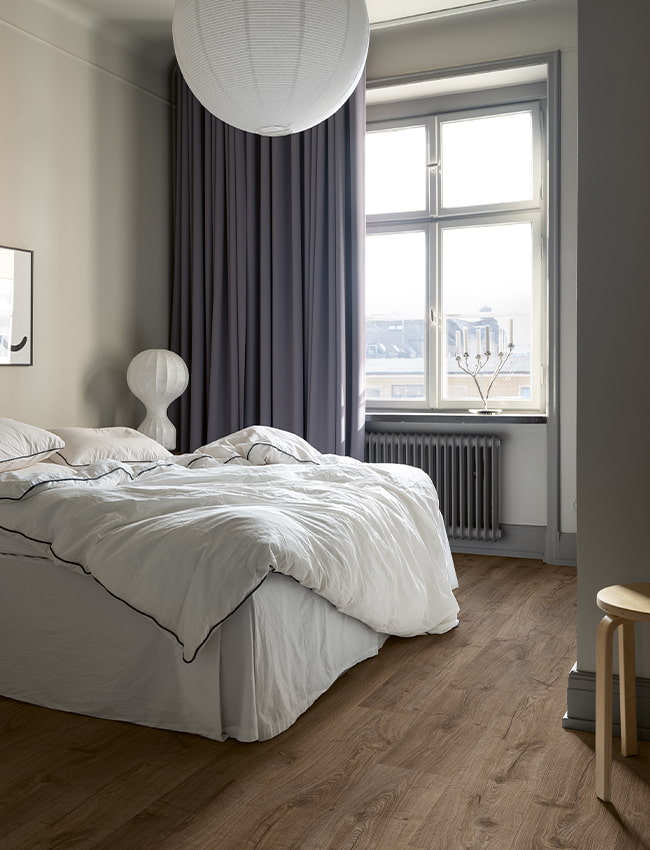 soveværelse med grå farver og et mørkebrunt laminatgulv